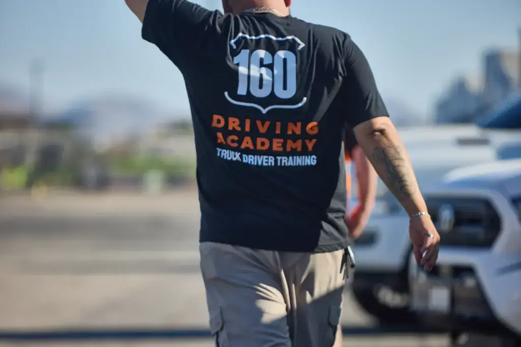 Person wearing 160 Driving Academy shirt outdoors