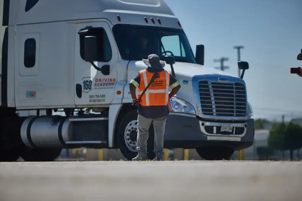 Instructor observing student driving academy truck