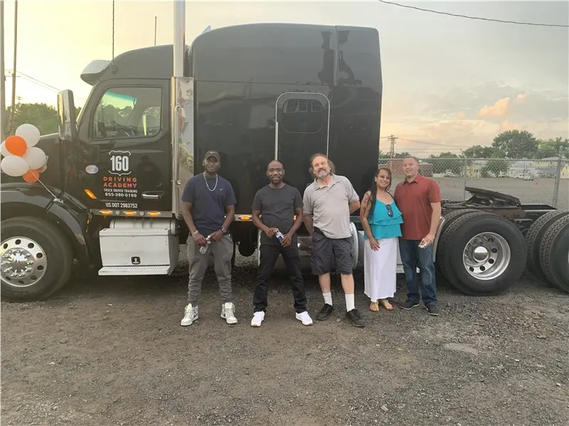 Five people standing beside a parked truck