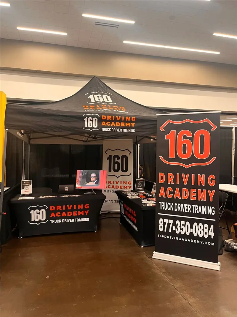 160 Driving Academy booth display with banner and tables