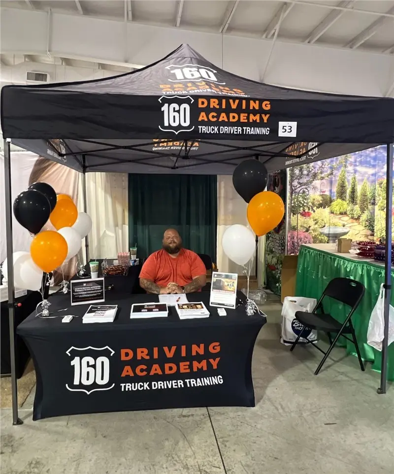 160 Driving Academy booth with seated representative