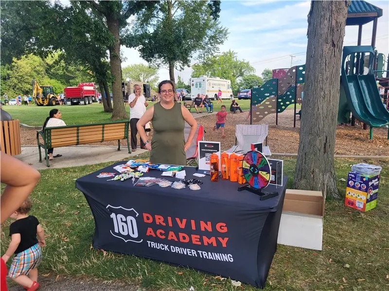 160 Driving Academy booth with smiling staff at event
