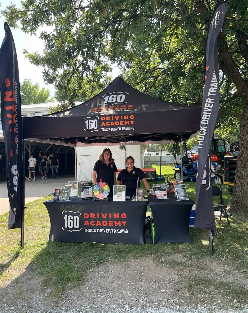 160 Driving Academy booth with two smiling representatives