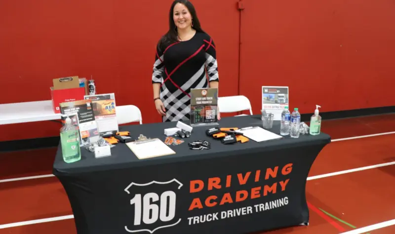 Person standing behind Driving Academy event booth