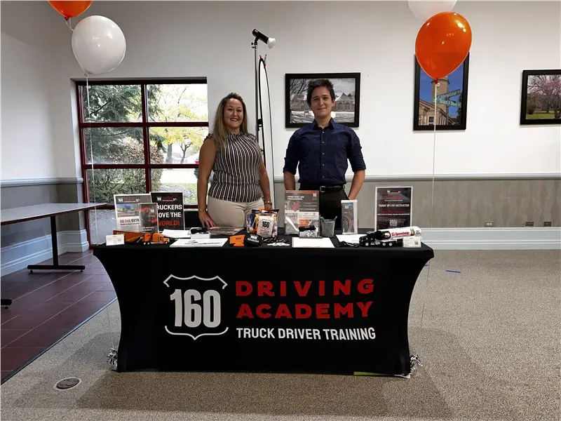 Two people at 160 Driving Academy event booth