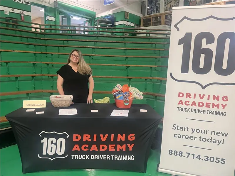 Woman at 160 Driving Academy event booth smiling