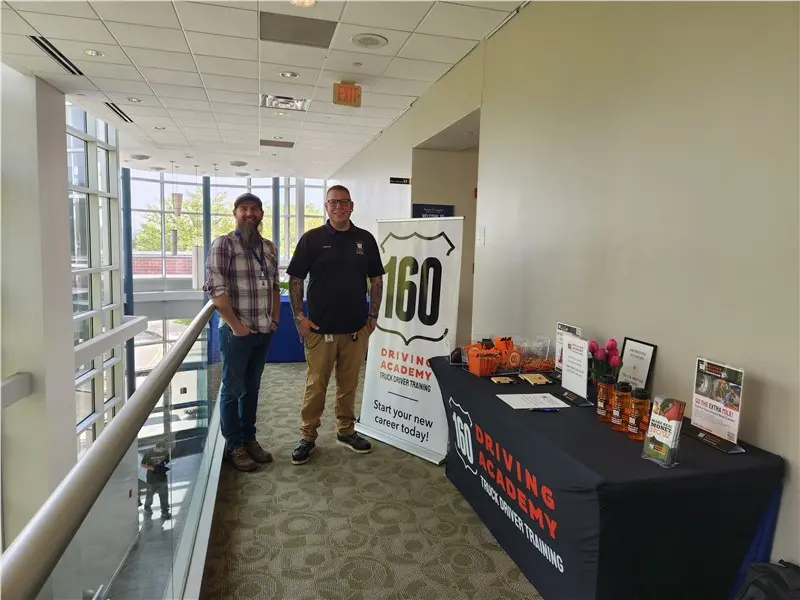 Two people standing at driving academy event booth