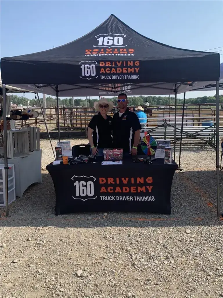 160 Driving Academy event booth with two smiling representatives