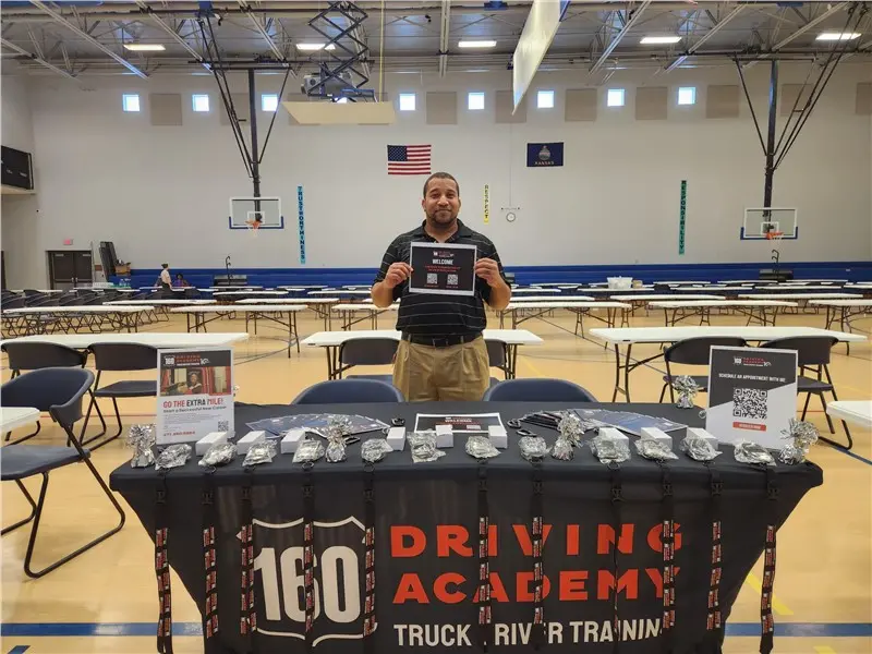 Man holds sign at driving academy event table