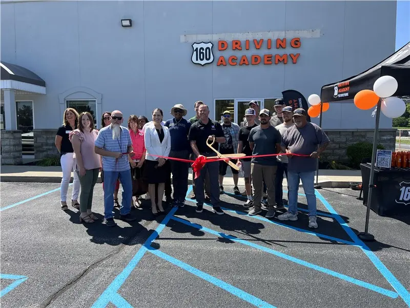 Group cutting ribbon at driving academy opening