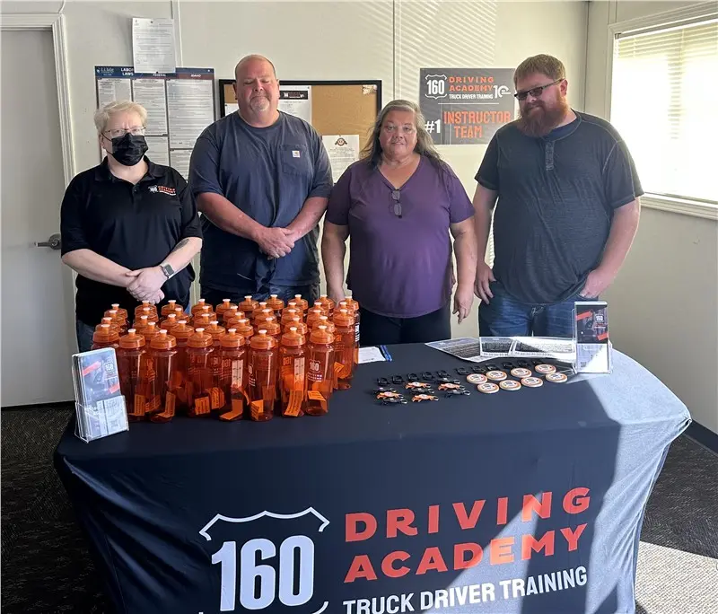 Driving Academy instructors standing behind branded table