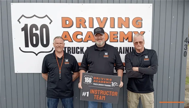 Three instructors standing in front of academy sign