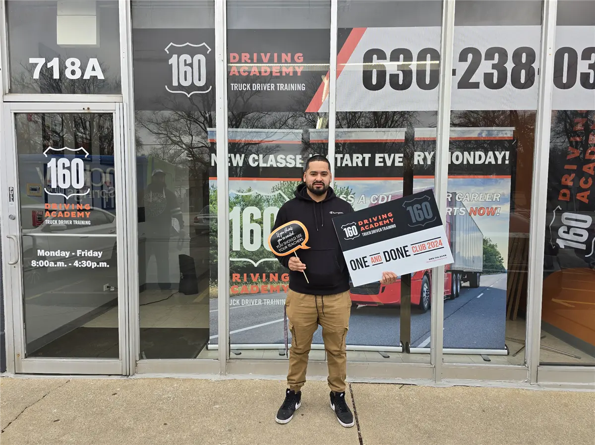 Man holding graduation sign outside 160 Driving Academy