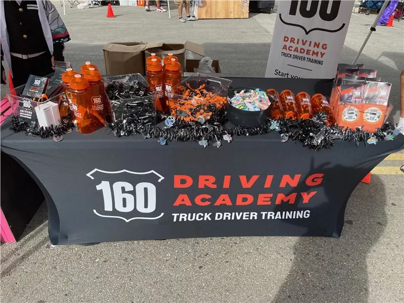 160 Driving Academy promotional table with merchandise displayed