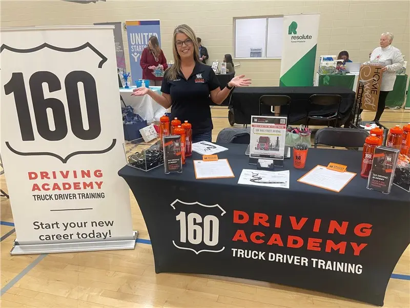 Woman presenting 160 Driving Academy booth display