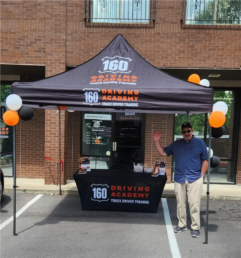 Man waving at 160 Driving Academy booth