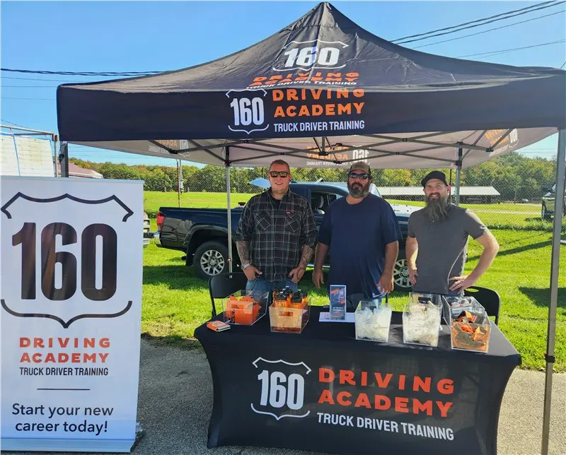 Three men at 160 Driving Academy booth