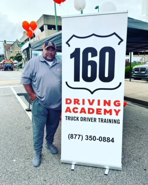 Person standing by 160 Driving Academy sign