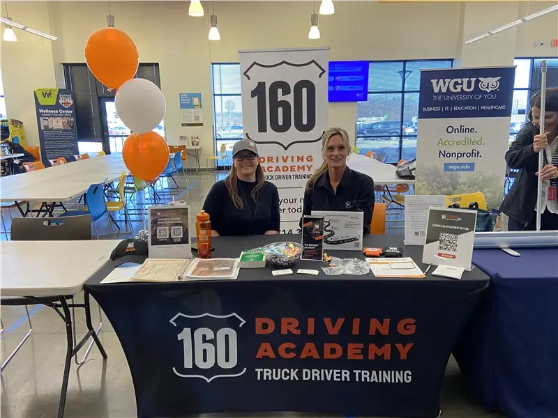 Two women at 160 Driving Academy booth