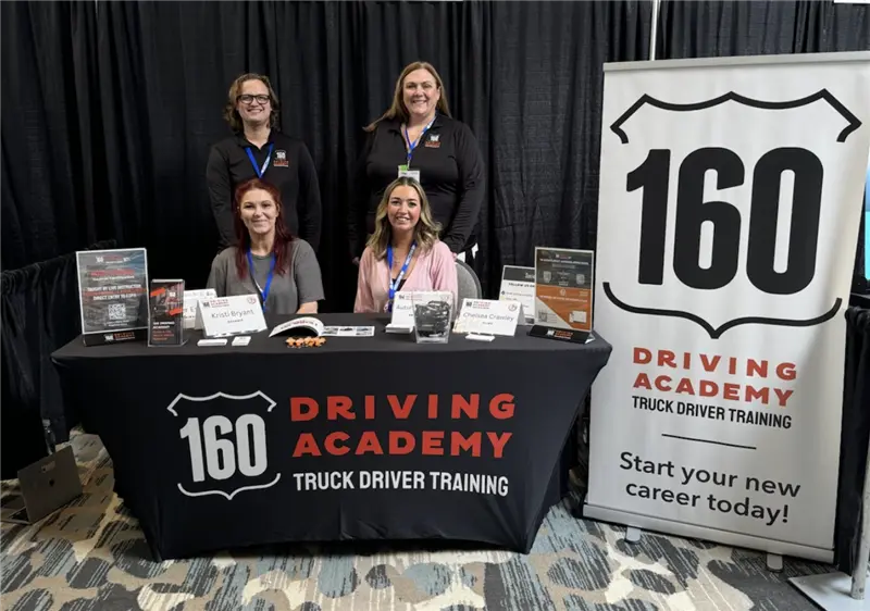 Driving Academy staff at recruitment booth smiling