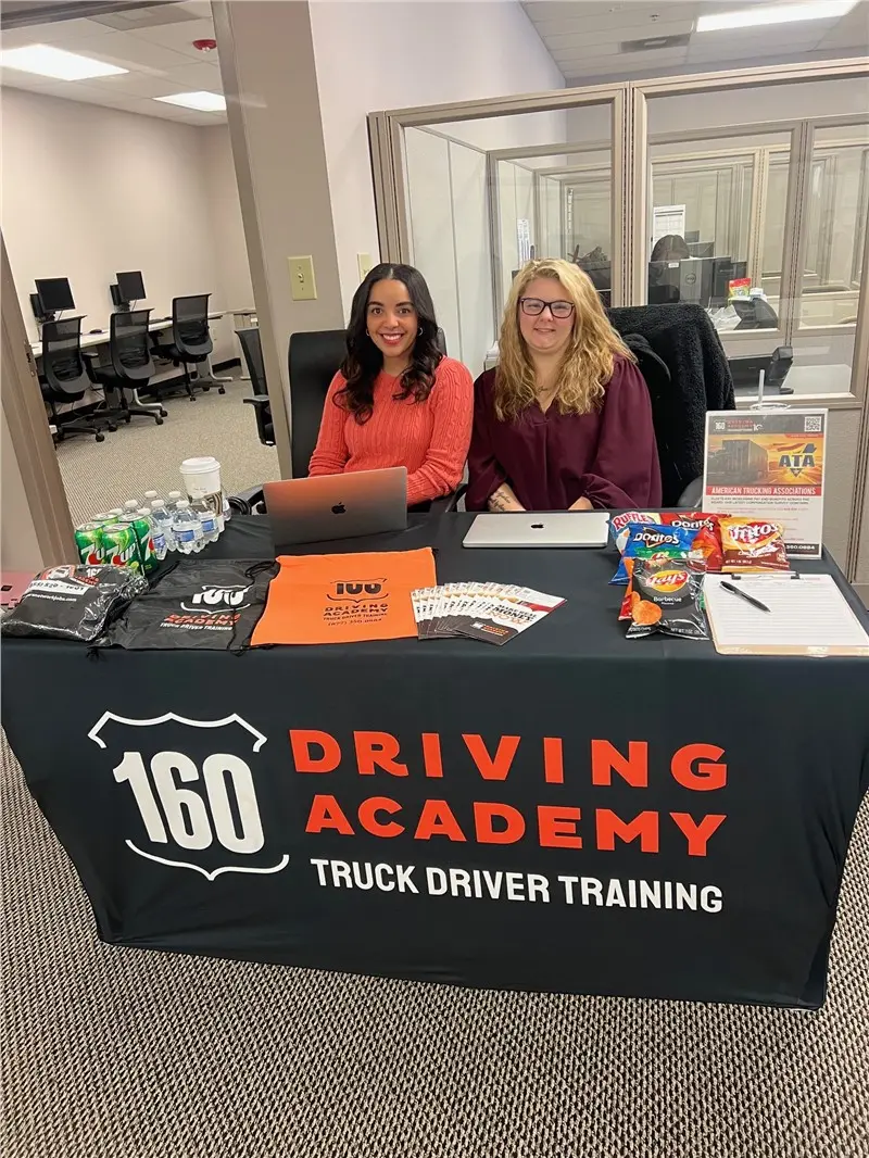Two women at recruitment desk, 160 Driving Academy