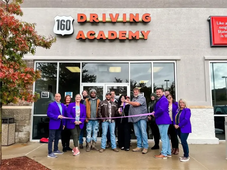 People cutting ribbon outside 160 Driving Academy building