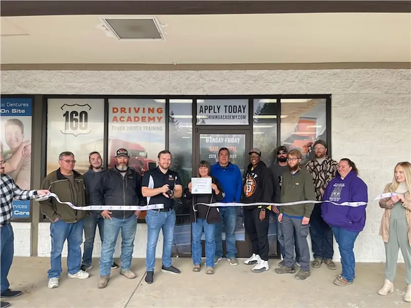 Group celebrating ribbon-cutting at driving academy