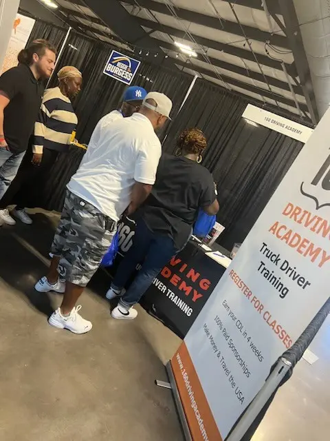 People attending Driving Academy information booth at event