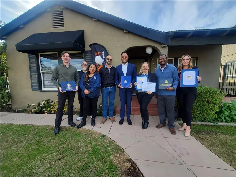 Group holding certificates in front of a building