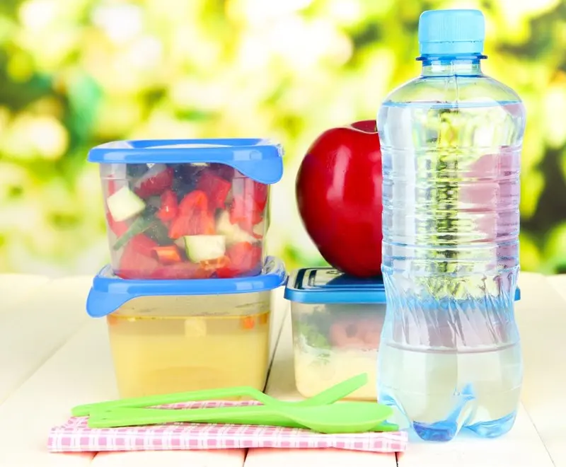 Containers of snacks, apple, water bottle on table