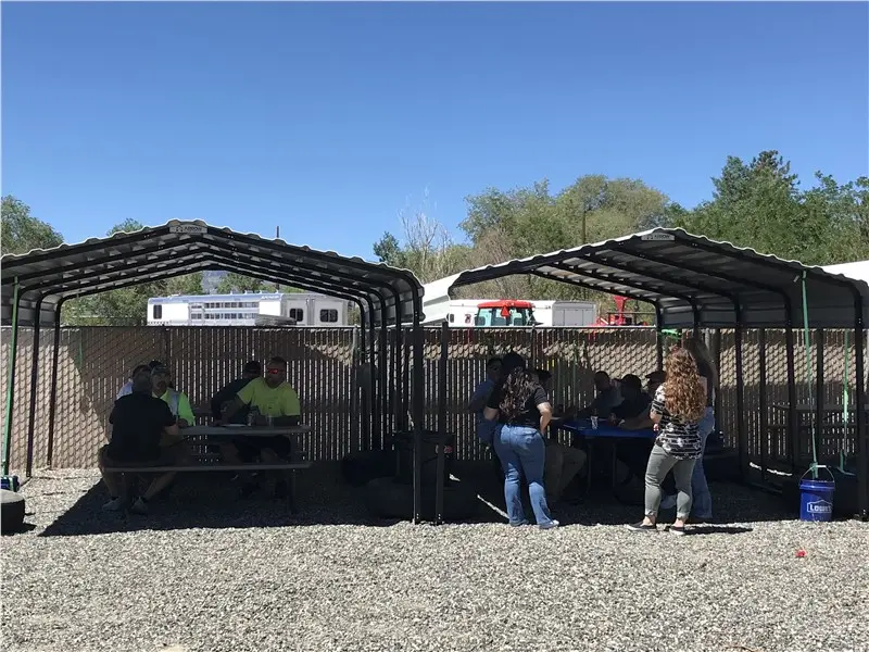People socializing under outdoor shelters in sunny weather