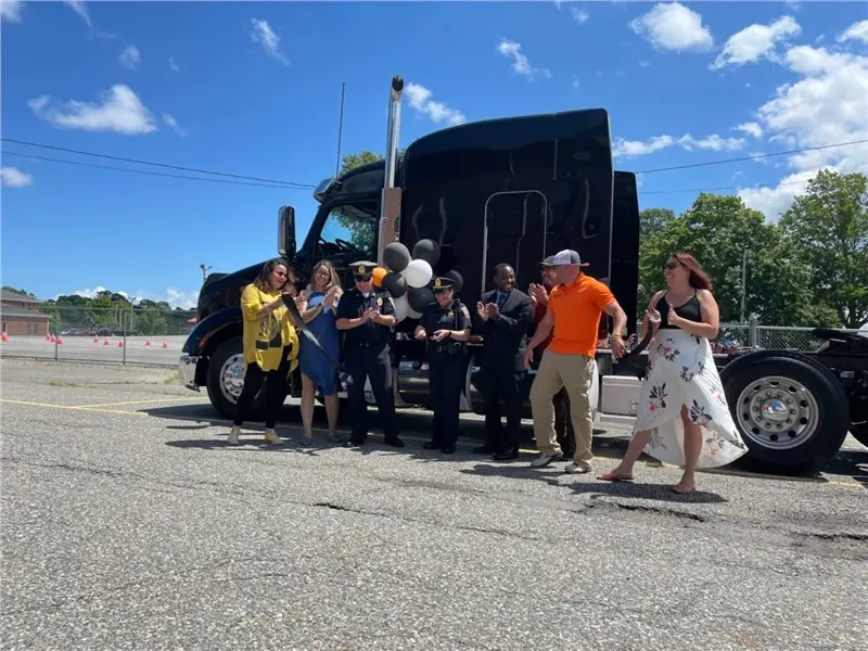 People celebrating near a large black truck