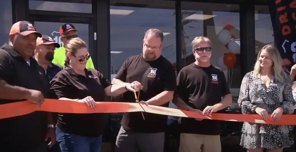 People participating in ribbon-cutting ceremony outside building
