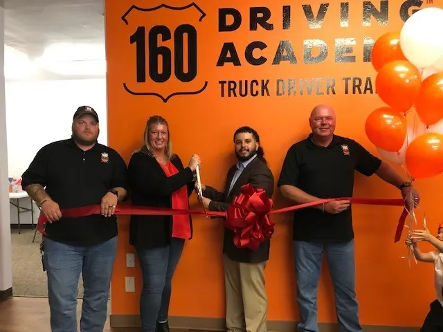 People celebrating ribbon-cutting at 160 Driving Academy