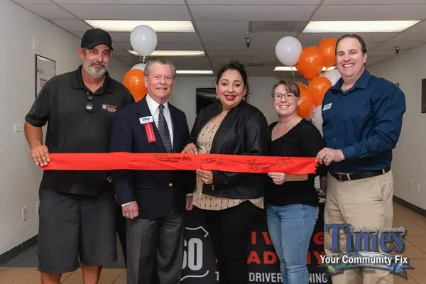 Group cutting ribbon at ceremony with balloons