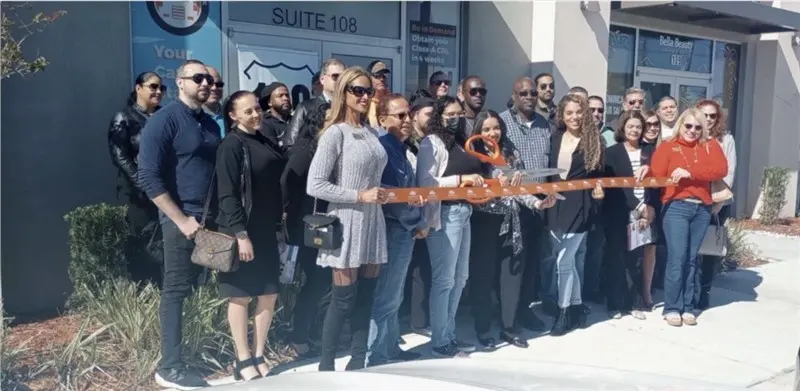 Group holding ribbon for cutting ceremony outside building