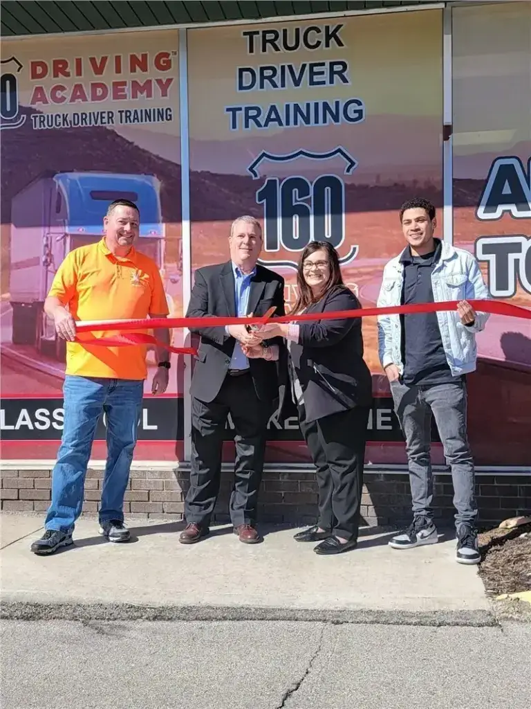 People cutting ribbon at truck driving academy opening
