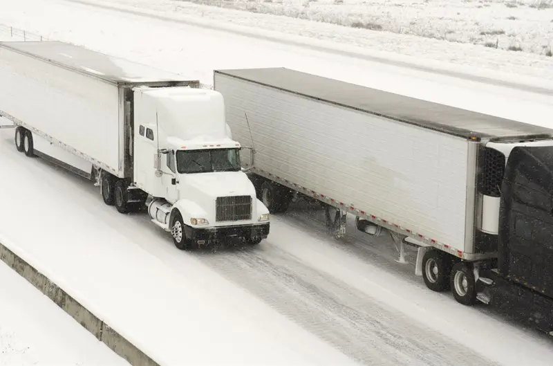 Truck driving on snowy highway with trailers attached