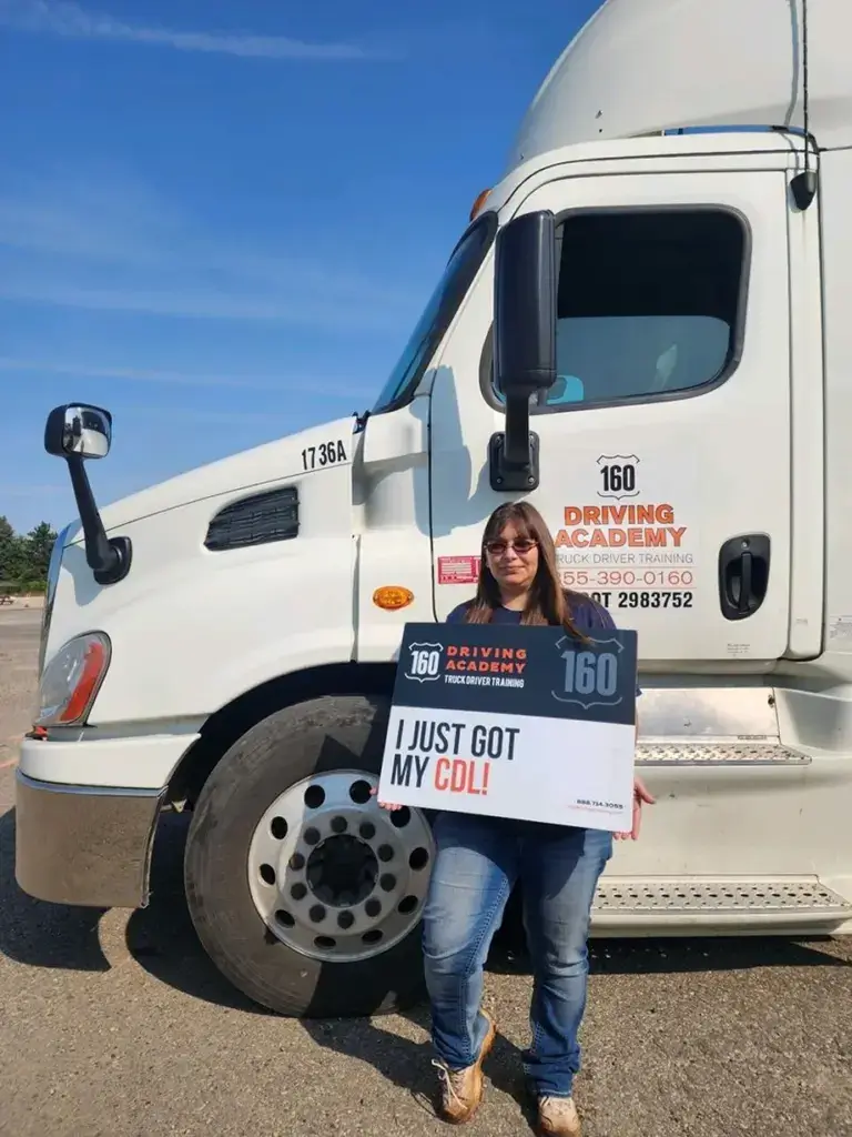 Woman holding sign beside academy truck