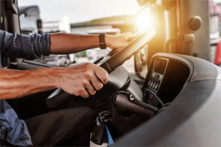 Truck driver gripping steering wheel at sunset