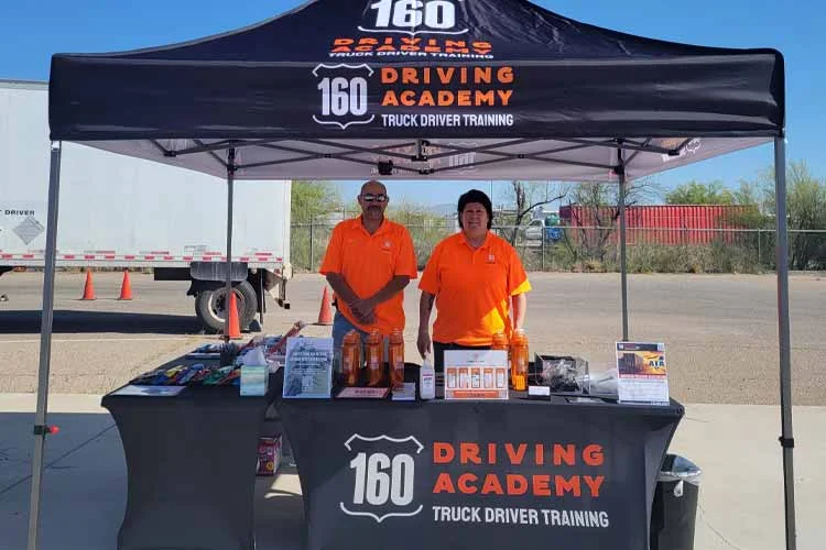 Two people at 160 Driving Academy booth
