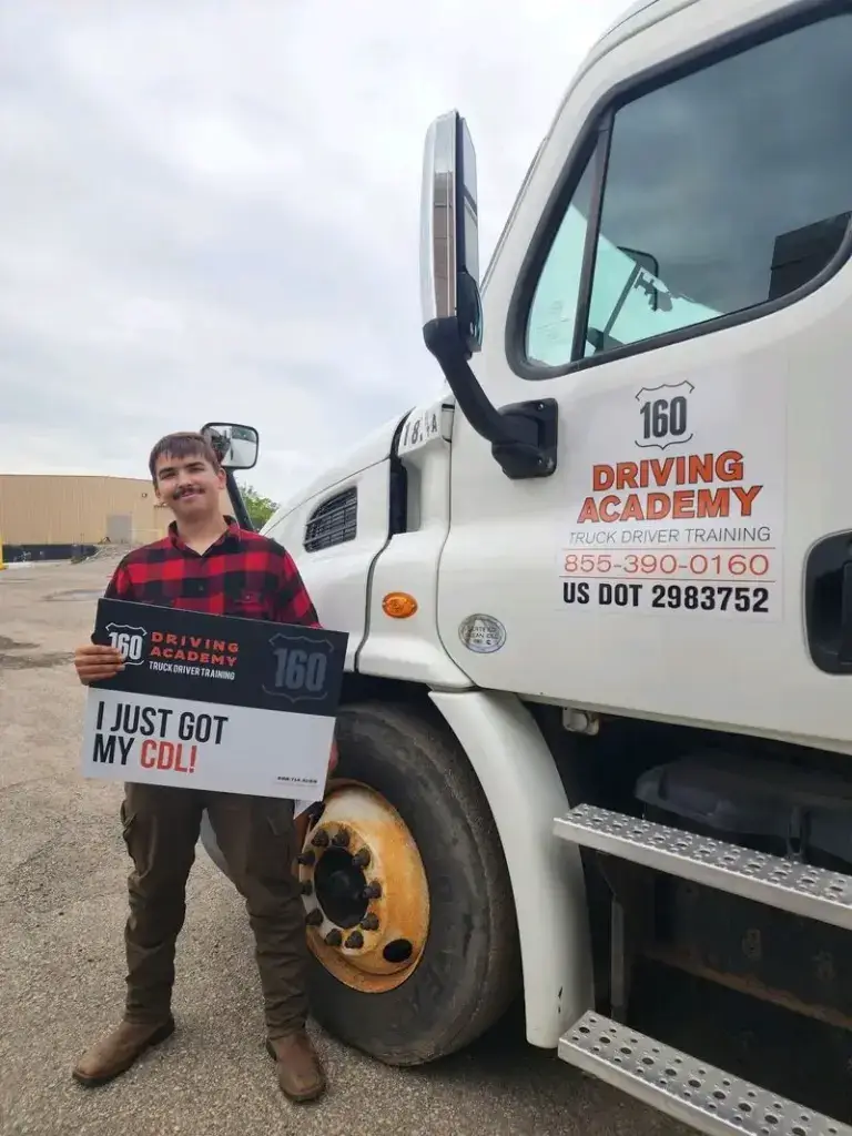 Graduate holding CDL certificate beside training truck