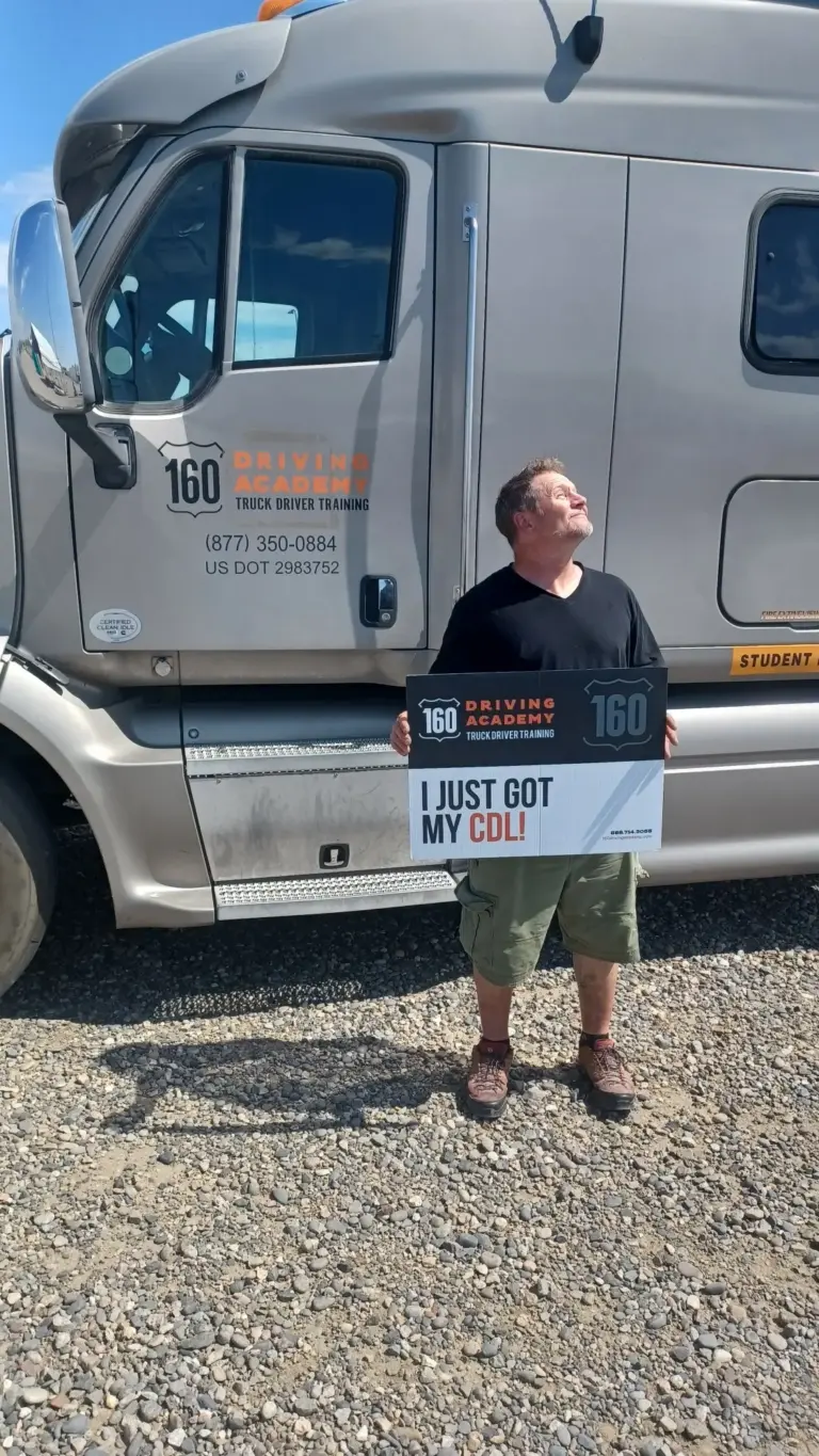 Graduate holding sign beside parked truck