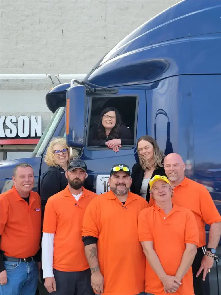 Group of truck drivers posing with blue truck