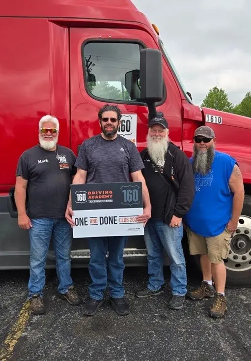 Four men smiling in front of red truck