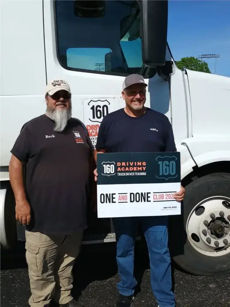 Two men standing beside a truck, smiling