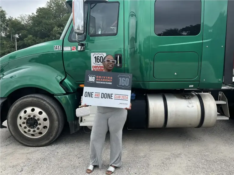 Graduate holding certificate in front of green truck