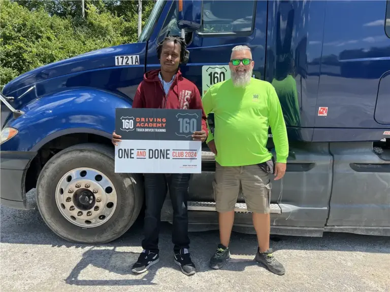 Graduates holding certificate beside academy truck