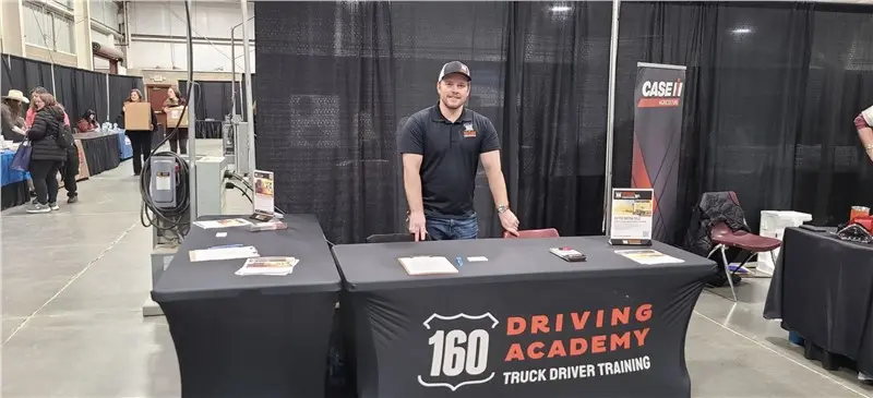 Man standing at 160 Driving Academy booth