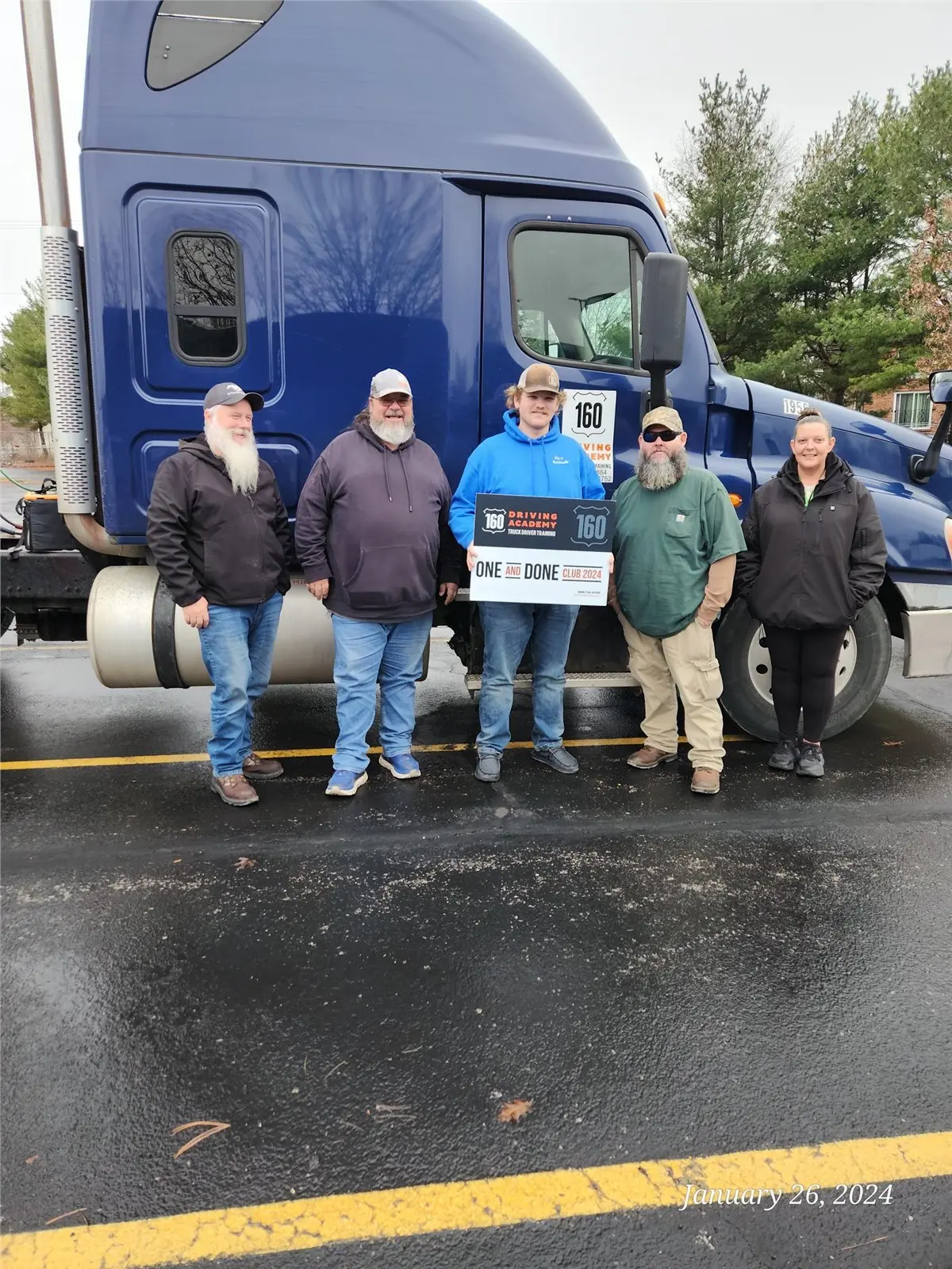 Graduated students pose in front of blue truck